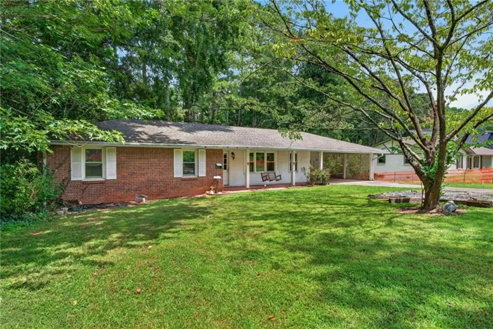 Brick exterior with white window shutters and a covered front porch featuring a porch swing