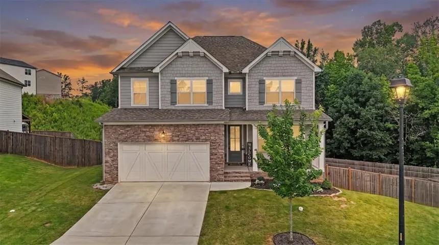Two-story residence featuring a stone and siding exterior, an attached two-car garage, and a concrete driveway