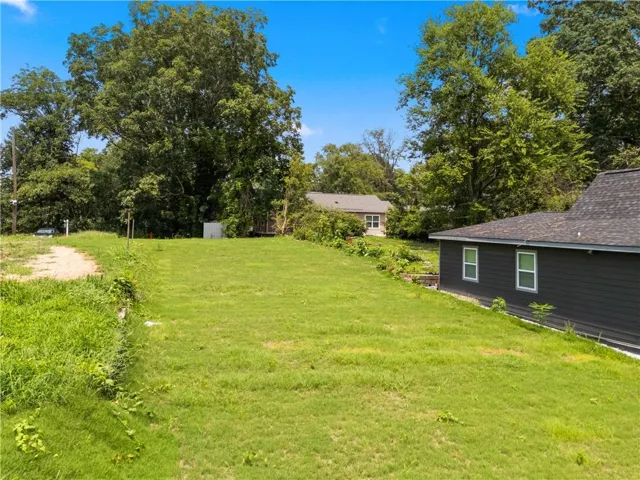 Expansive grassy yard area with surrounding mature trees and natural landscaping