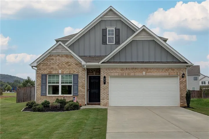 Brick and siding exterior featuring a prominent gable roofline and a two-car garage