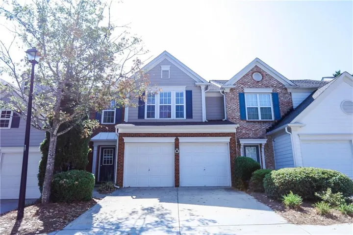 Two-car garage with white doors, brick and siding exterior, blue window shutters, and a covered entry