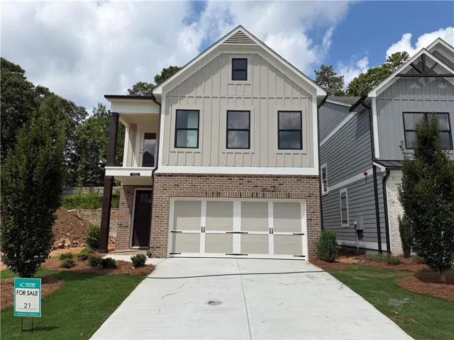 Modern farmhouse-style exterior featuring a board-and-batten facade, brick detailing, black-framed windows, an attached two-car garage, and a covered entry porch