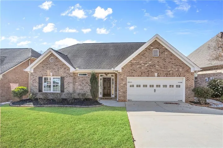 View of front facade featuring roof with shingles, concrete driveway, a front yard, brick siding, and an attached garage