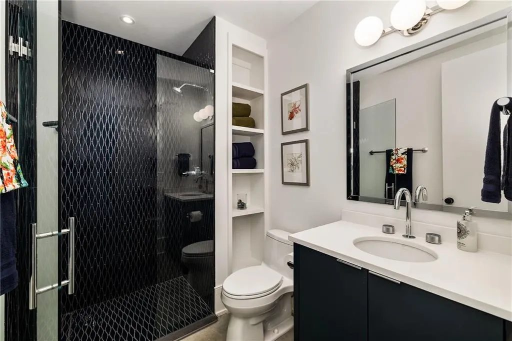 Main floor Secondary Hall Bath that serves Main Floor Bedroom  featuring an enclosed shower, vanity, and toilet