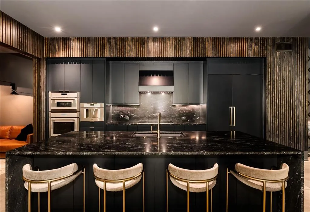 Kitchen featuring double oven, sink, a center island with sink, and a kitchen bar