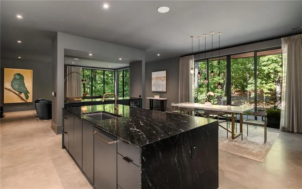 Kitchen with hanging light fixtures, sink, dark stone counters, and a kitchen island with sink