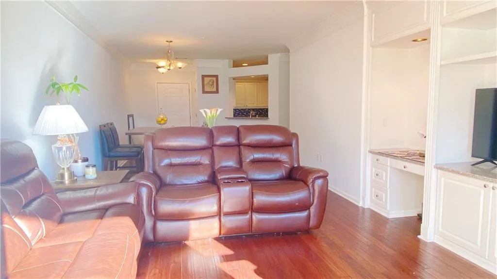 Wood-finish flooring throughout, crown molding, built-in desk, built-in media cabinet, and a chandelier lighting fixture