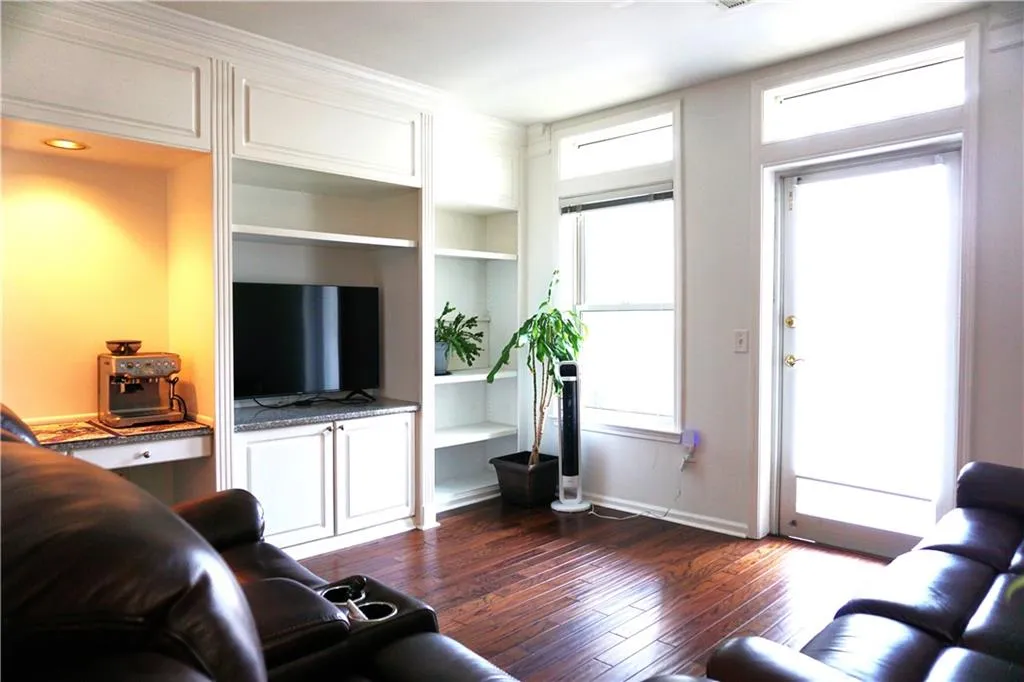 Hardwood-finish flooring, built-in shelving, transom windows, built-in cabinetry with stone-look countertop, and a glass-paneled door