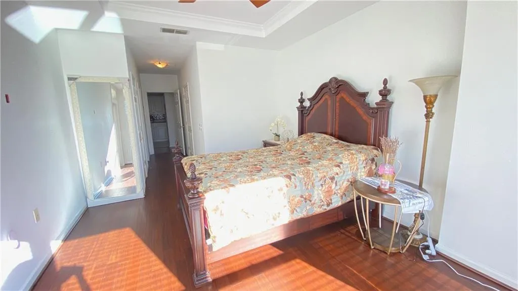 Tray ceiling detail, wood-finish flooring, white walls, recessed lighting, and a well-lit hallway