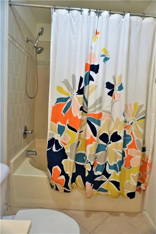Bathtub with a wall-mounted showerhead, tiled surround, and chrome fixtures