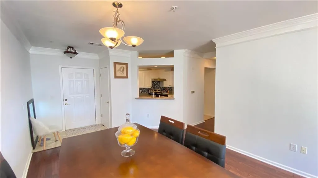 Built-in shelving with crown molding, integrated desk area with storage, hardwood flooring, and large windows with transom panels