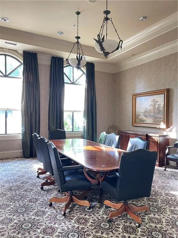 Coved ceilings with recessed lighting, two ornate hanging light fixtures, arched windows with dark drapery, and patterned carpeting