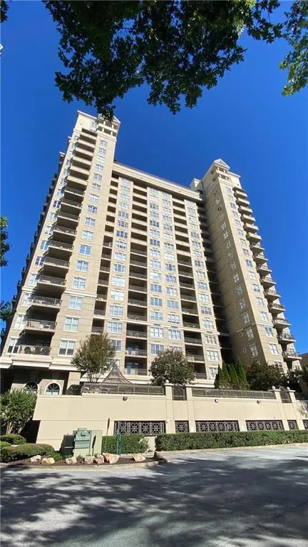 Multi-story building featuring numerous private balconies, a stucco exterior, and ground-level landscaping