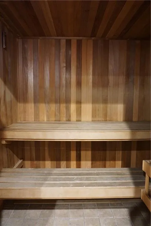 Wood-paneled interior featuring a tiered bench system and a tiled floor