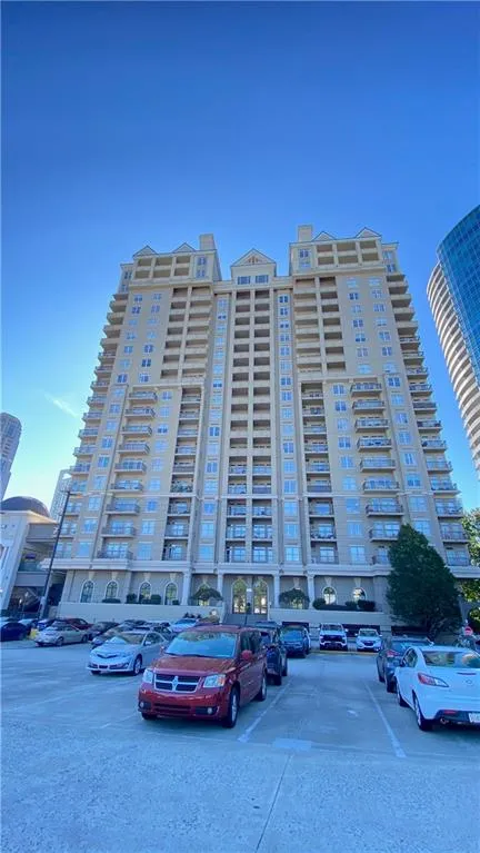 Multi-story residential building with numerous balconies and a visible parking area
