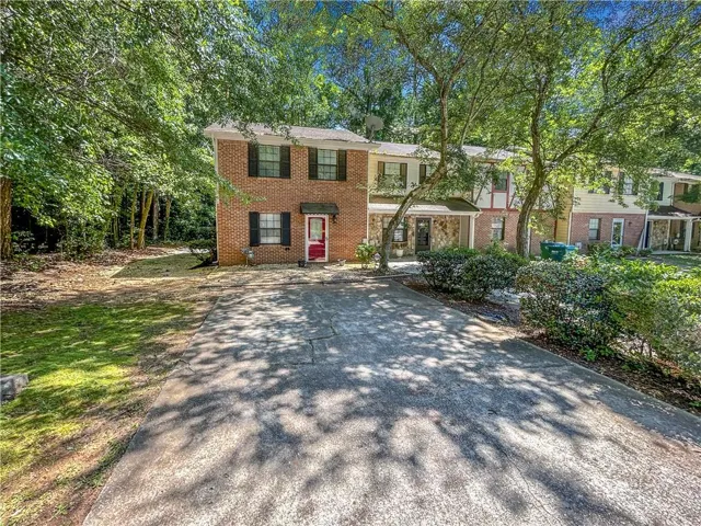 Brick exterior with black shutters and a red entry door