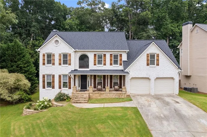 White brick exterior with a dark shingle roof