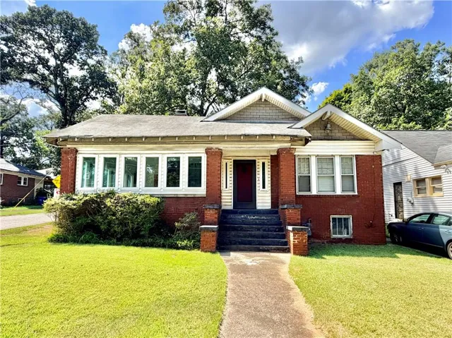 Brick exterior with a gabled roofline, front porch, and mature landscaping