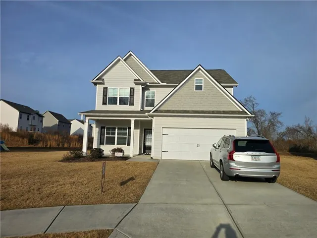 Two-story residence featuring light gray siding with dark shutters and white trim accents