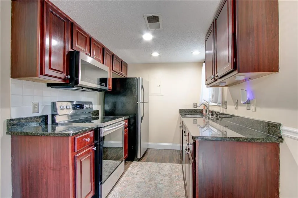 Kitchen featuring stainless steel appliances, wood cabinetry, and tile backsplash