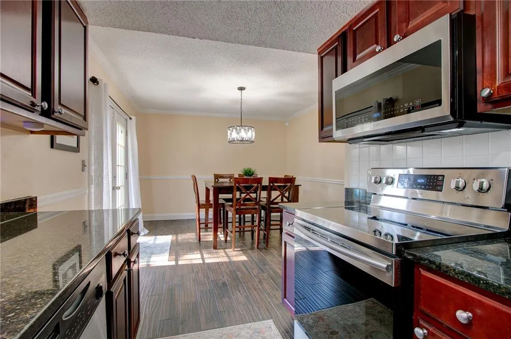 Kitchen featuring stainless steel appliances, wood cabinetry, and tile backsplash