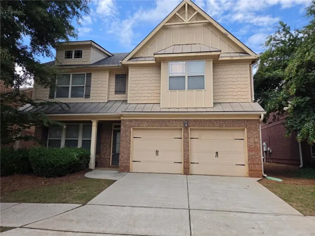Two-story residence featuring a brick and siding facade, covered entry porch, and a two-car attached garage