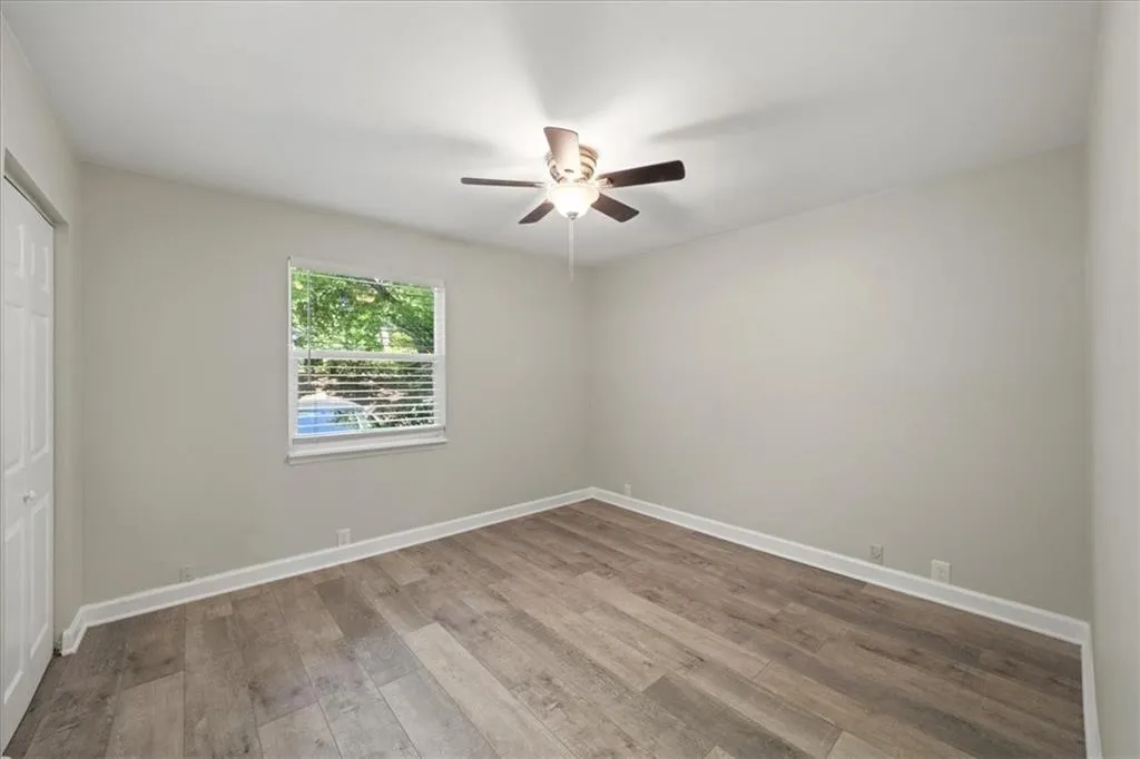 Empty room with wood finished floors, ceiling fan, and baseboards