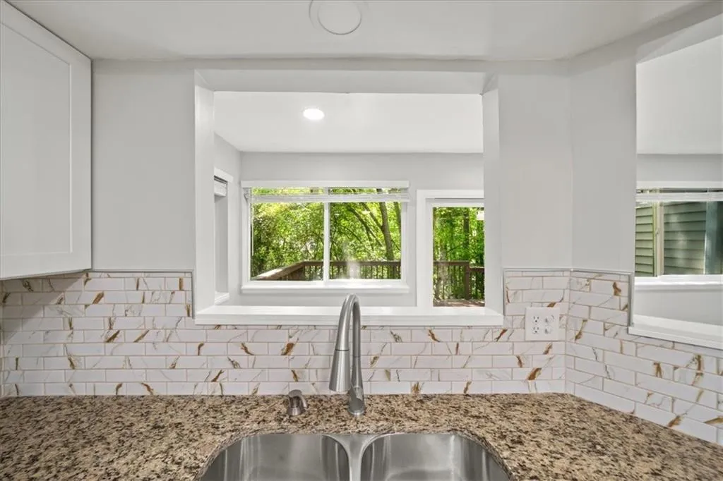 Kitchen featuring a sink, white cabinets, backsplash, plenty of natural light, and recessed lighting