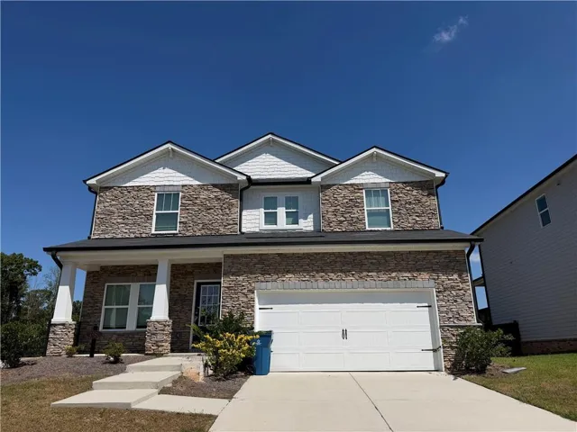 Two-story residence featuring a stone and siding exterior, prominent front gable accents, an attached two-car garage, and a covered front porch with white columns