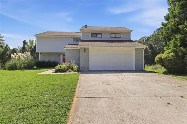 Two-story exterior with siding and stone facade, attached two-car garage, and concrete driveway