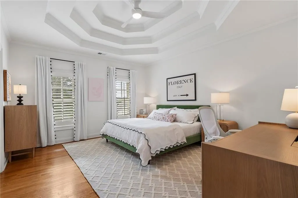 Bedroom with crown molding, ceiling fan, a raised ceiling, and hardwood / wood-style floors