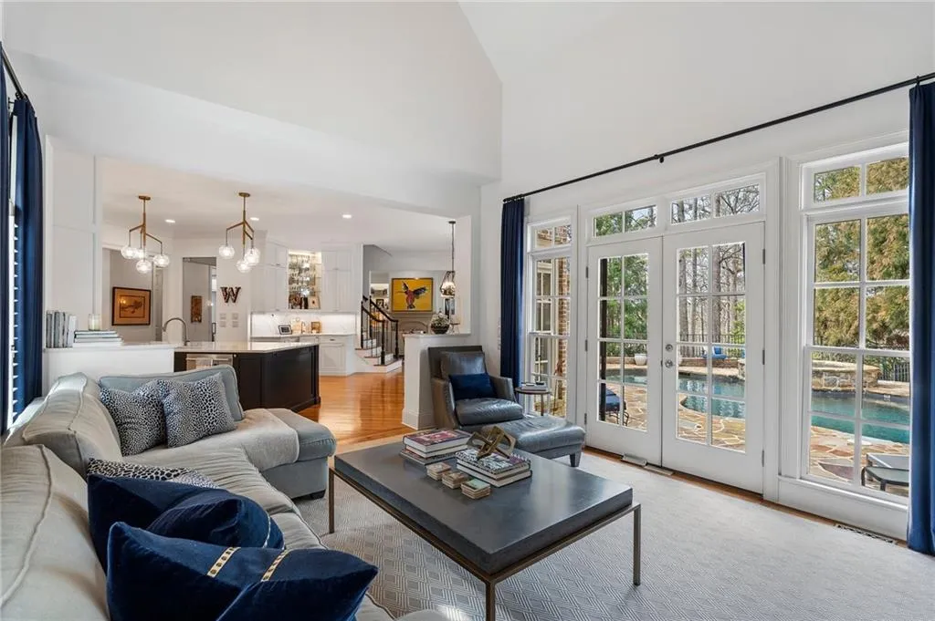 Living room featuring french doors, a high ceiling, a chandelier, and light hardwood / wood-style floors