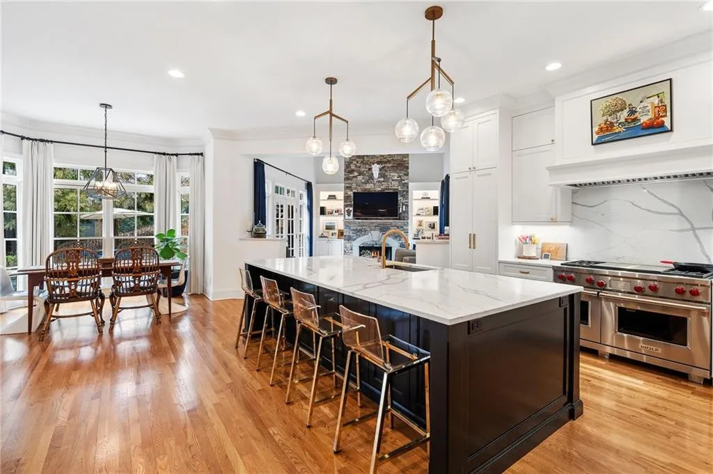 Kitchen with white cabinetry, double oven range, a large island, and decorative light fixtures