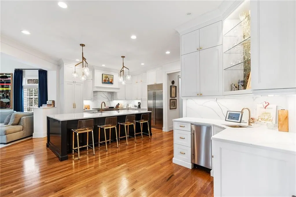 Kitchen with white cabinetry, sink, pendant lighting, and stainless steel built in fridge
