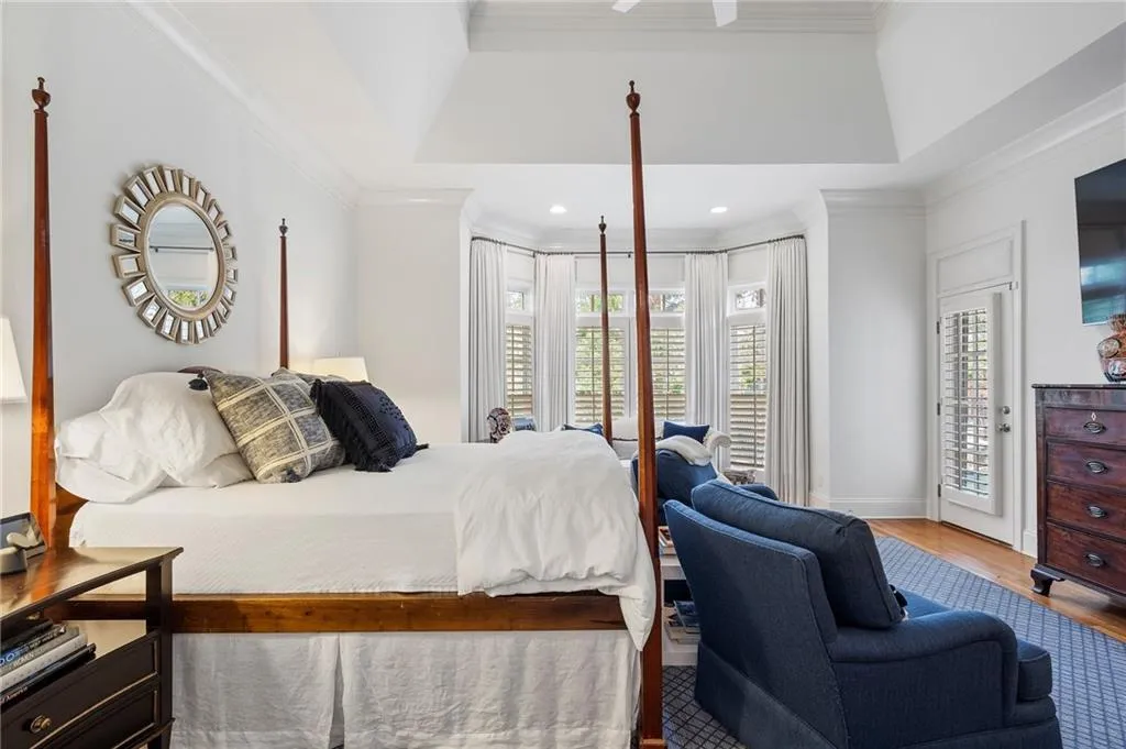 Bedroom featuring hardwood / wood-style floors, crown molding, a raised ceiling, and access to outside