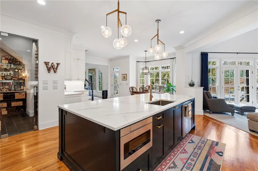 Kitchen with a kitchen island with sink, sink, pendant lighting, and white cabinets