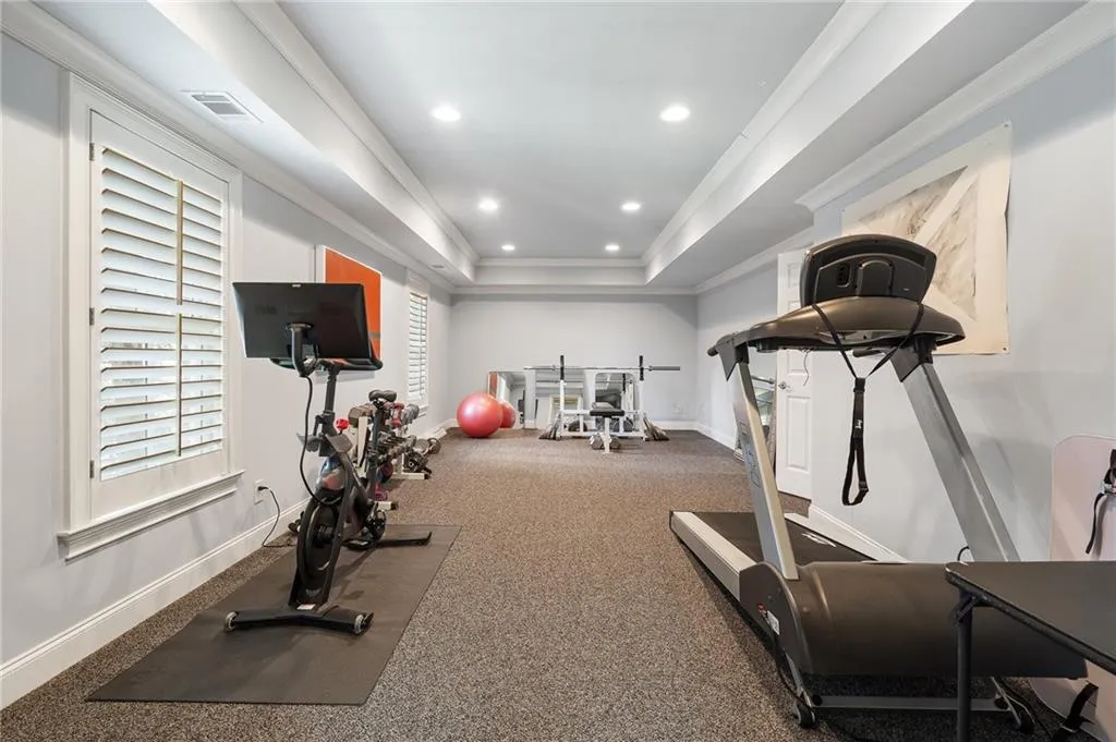 Exercise room featuring crown molding, a raised ceiling, and a healthy amount of sunlight