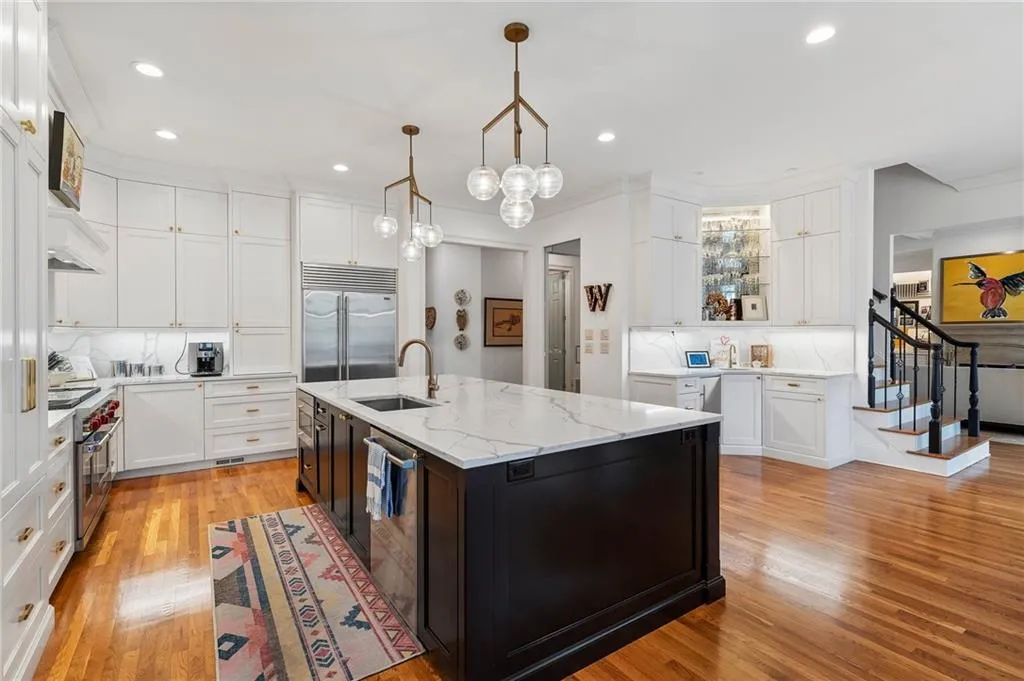Kitchen with pendant lighting, sink, a kitchen island with sink, high end appliances, and white cabinets