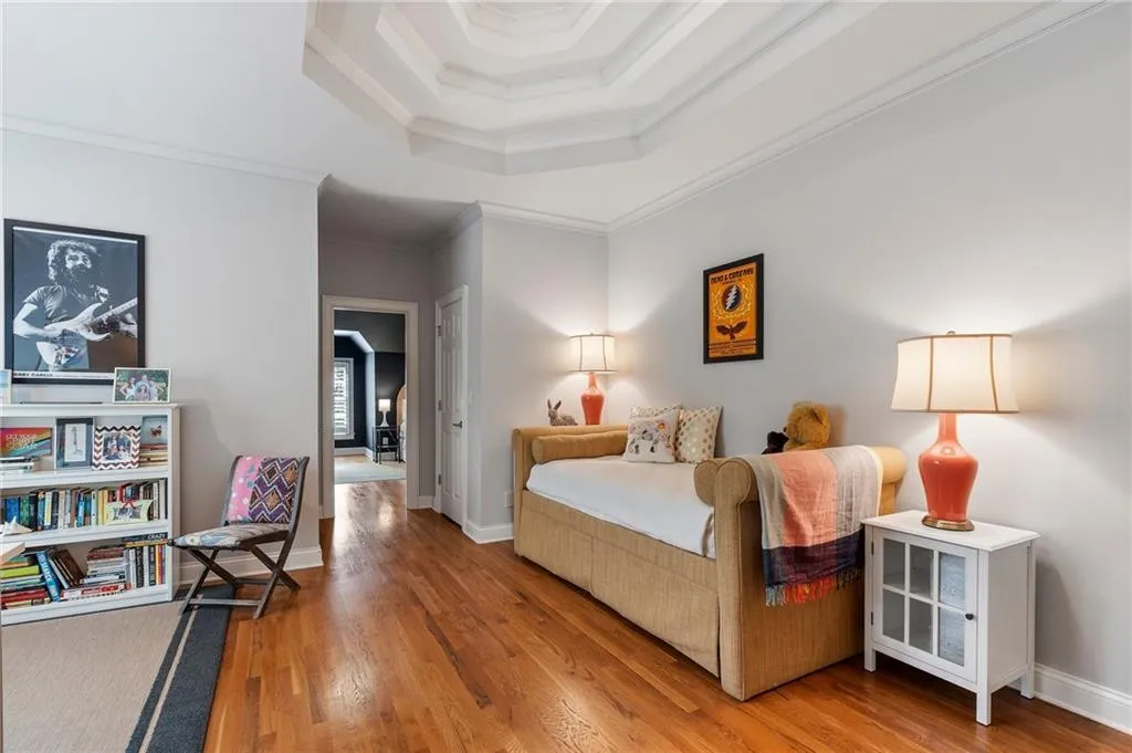 Bedroom with ornamental molding, hardwood / wood-style floors, and a tray ceiling