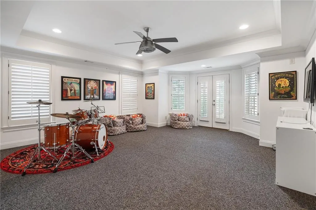 Playroom featuring crown molding, ceiling fan, a raised ceiling, and dark carpet