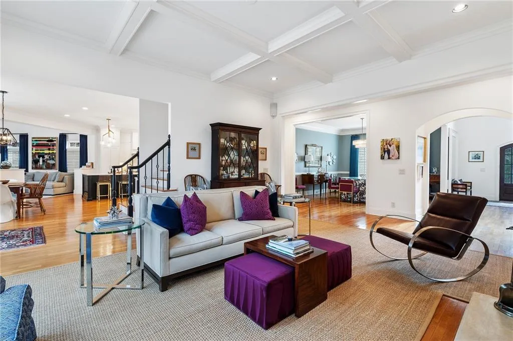 Living room with beamed ceiling, coffered ceiling, a chandelier, and light hardwood / wood-style flooring