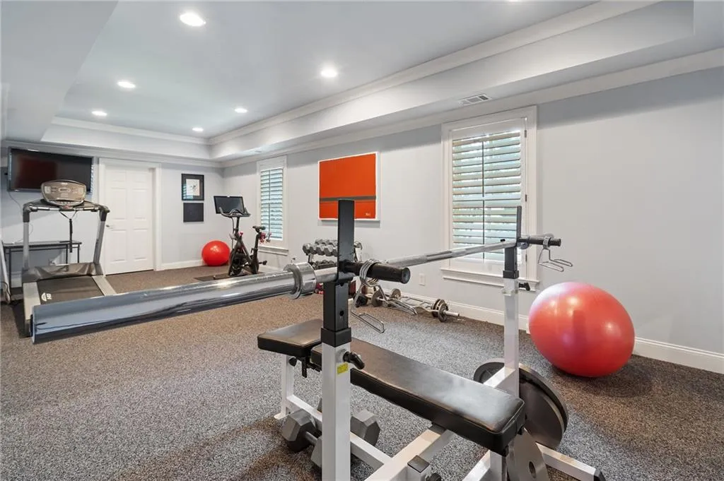 Workout room with a raised ceiling and ornamental molding