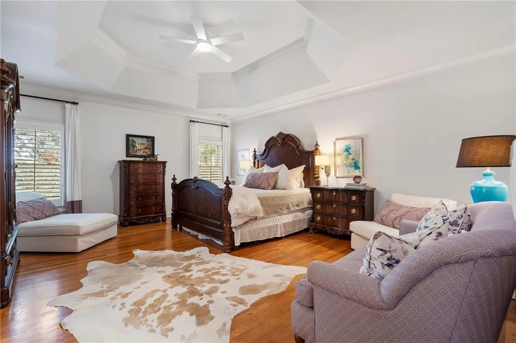 Bedroom featuring hardwood / wood-style flooring, ornamental molding, a tray ceiling, and multiple windows