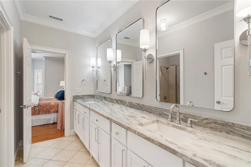 Bathroom featuring tile patterned flooring, vanity, crown molding, and a shower