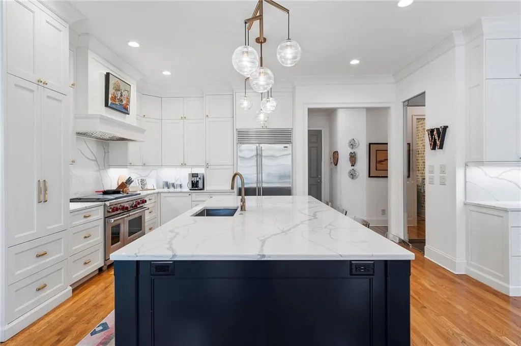Kitchen with high quality appliances, sink, a center island with sink, and decorative light fixtures