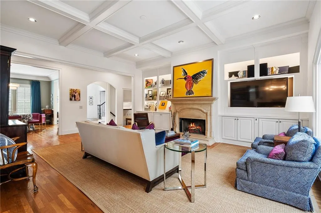 Living room with built in features, light wood-type flooring, coffered ceiling, a premium fireplace, and beam ceiling