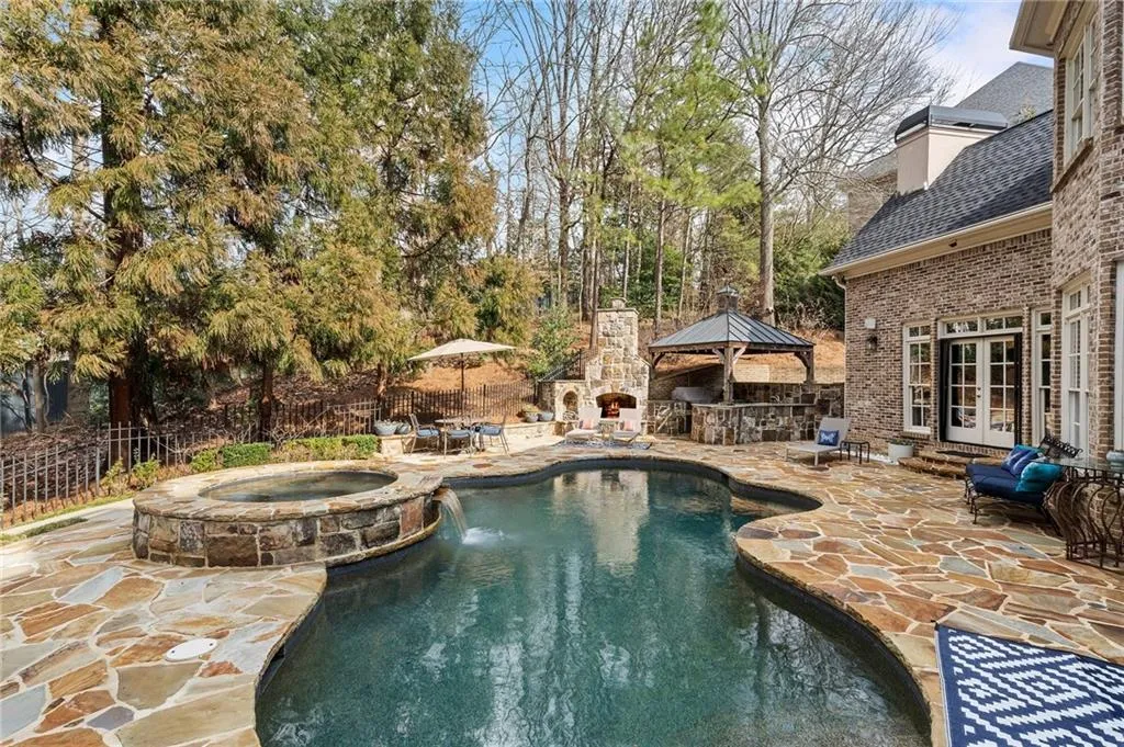 View of pool with an in ground hot tub, a gazebo, a patio, and an outdoor stone fireplace