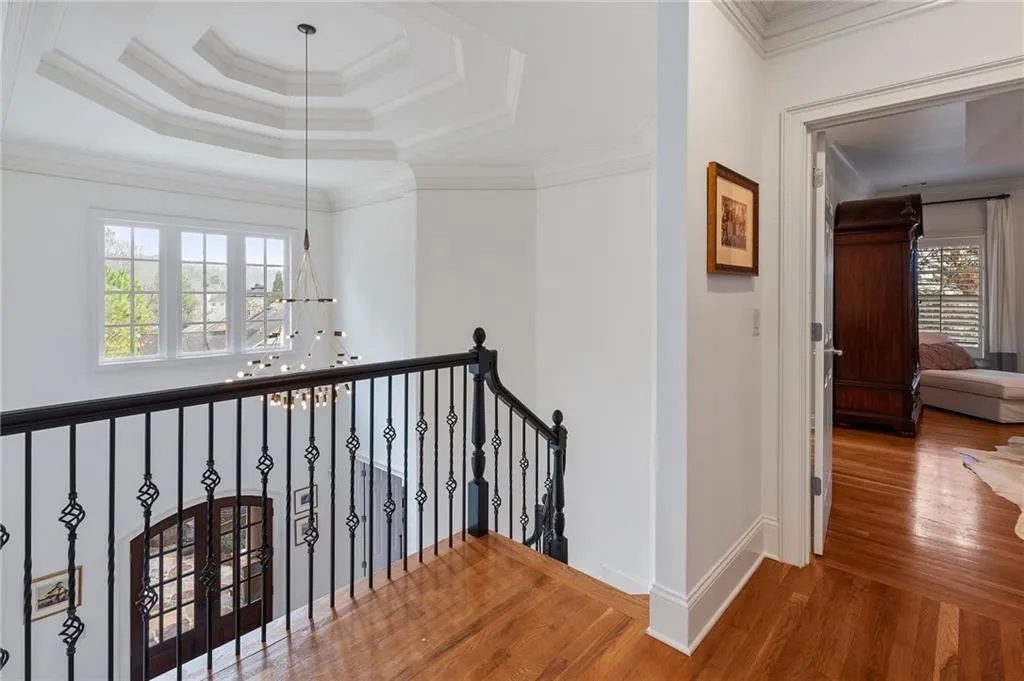 Hall with a raised ceiling, crown molding, and wood-type flooring