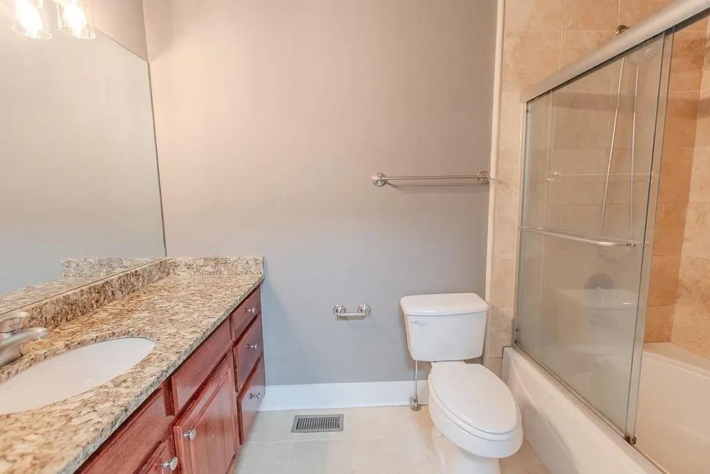 Full bathroom featuring combined bath / shower with glass door, oversized vanity, toilet, and tile floors Full bathroom featuring combined bath / shower with glass door, oversized vanity, toilet, and tile floors
