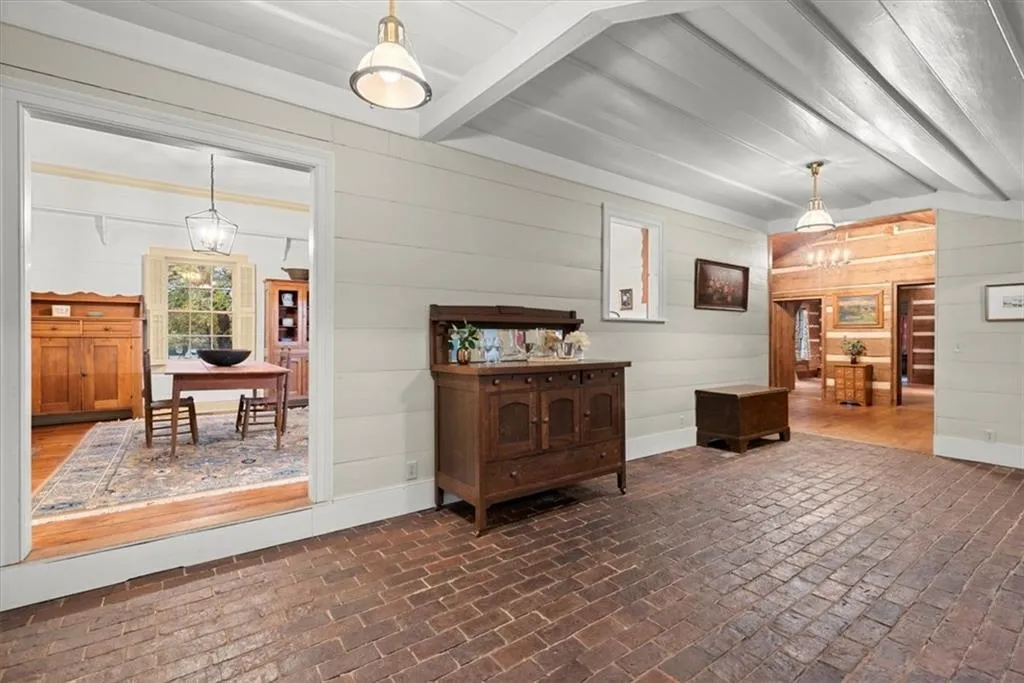 Large sunroom is one of the spaces that connects the original farmhouse to the log cabin addition. This open hallway features brick flooring - look for the tiny antebellum raccoon footprints!